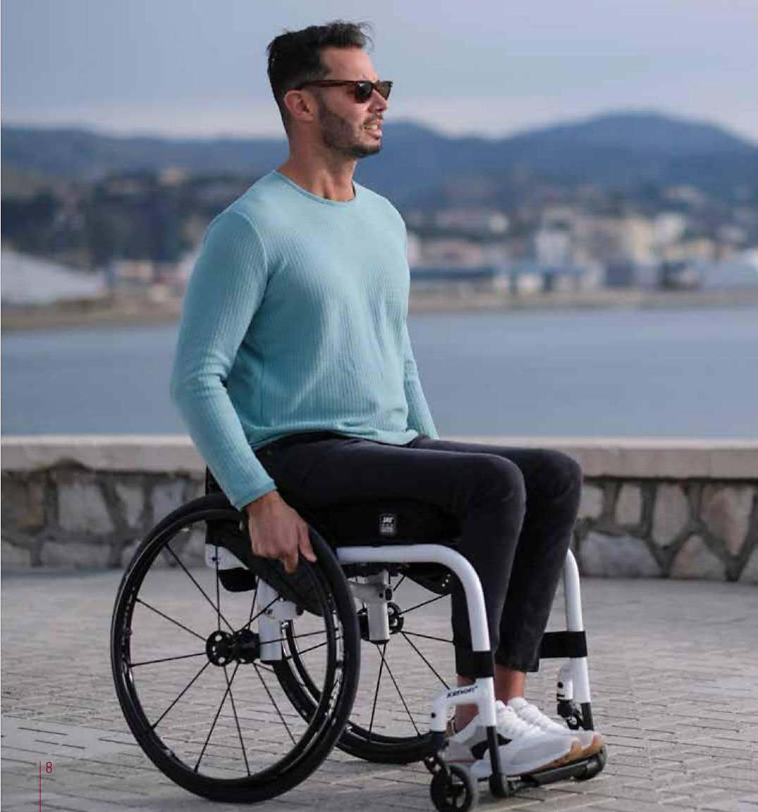 handicapé en fauteuil avec homme en pull bleu qui teste un fauteuil en bord de mer pour méridienne médicale